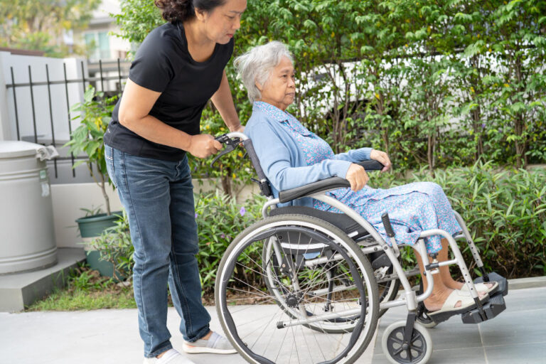 caregiver assisting senior in wheelchair outdoors