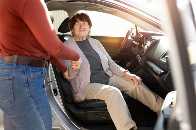 elderly person receiving help getting into vehicle safely