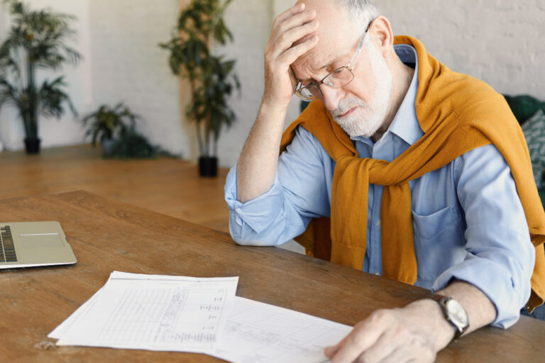 elderly man stressed reviewing medical bills and long term care expenses