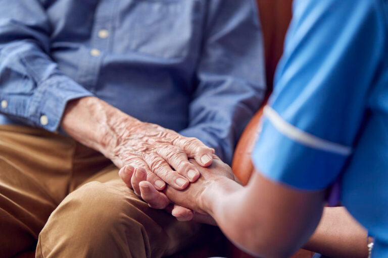 caregiver holding elderly person's hand showing support and compassion
